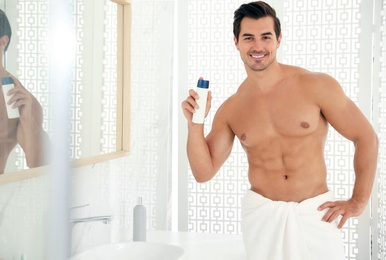 Handsome young man with deodorant in bathroom