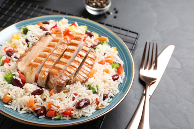 Photo of Tasty rice with beans and meat served on black table, closeup