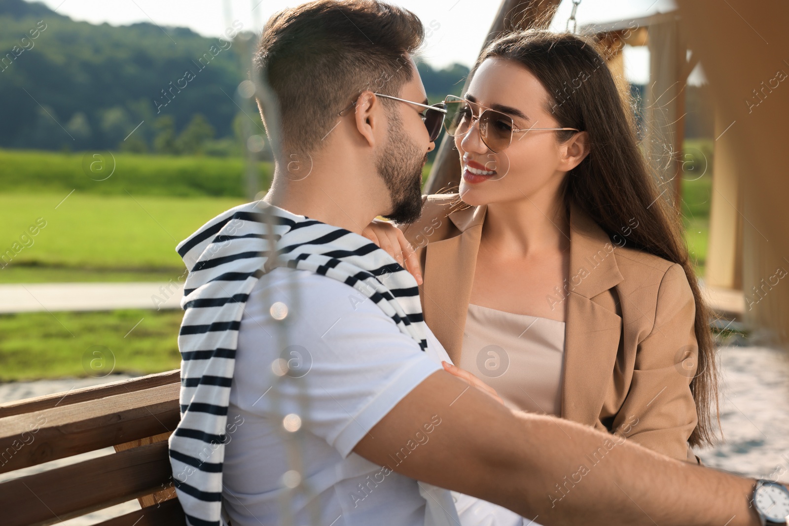 Photo of Romantic date. Beautiful couple spending time together on swing bench outdoors