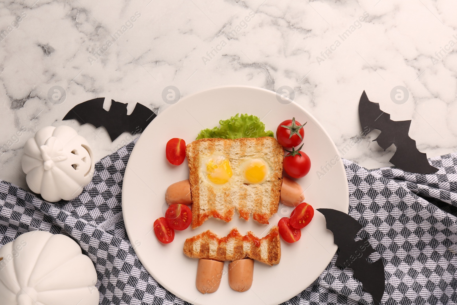 Photo of Cute monster sandwich with cherry tomatoes, fried eggs and sausages on white marble table, flat lay and space for text. Halloween snack