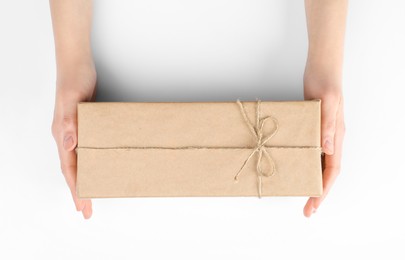 Photo of Woman holding parcel wrapped in kraft paper on white background, top view