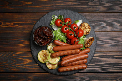 Tasty grilled sausages served on wooden table, top view