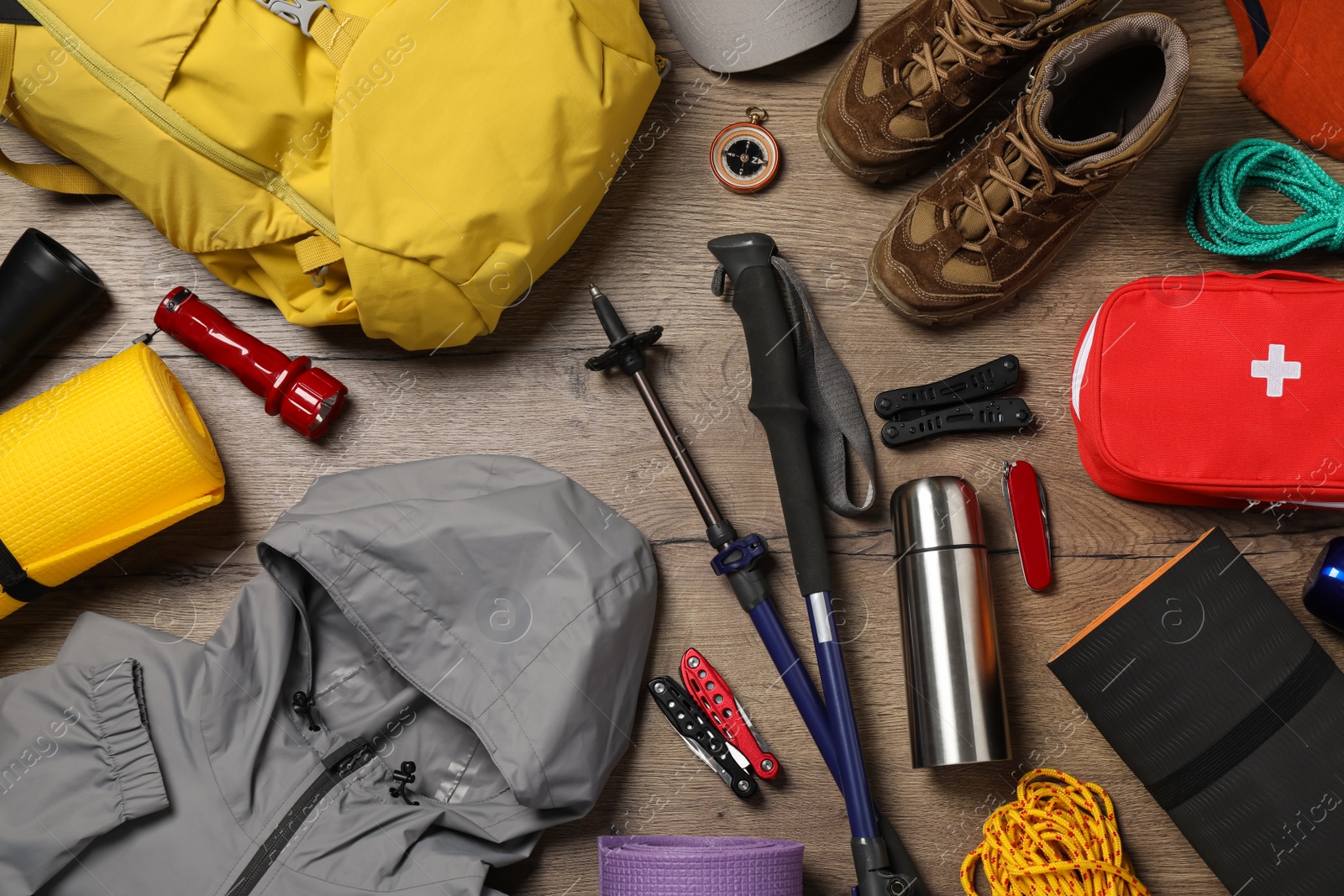 Photo of Flat lay composition with trekking poles and other hiking equipment on wooden background