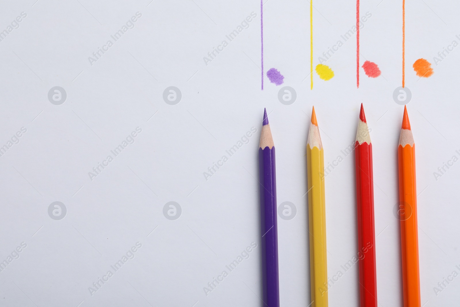 Photo of Colorful pencils with swatches on white background, top view