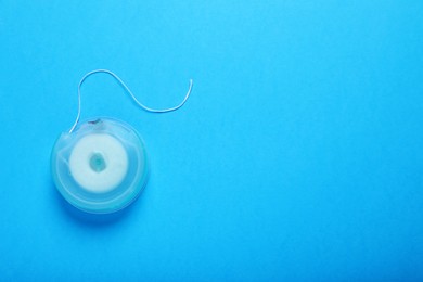 Photo of Container with dental floss on light blue background, top view. Space for text