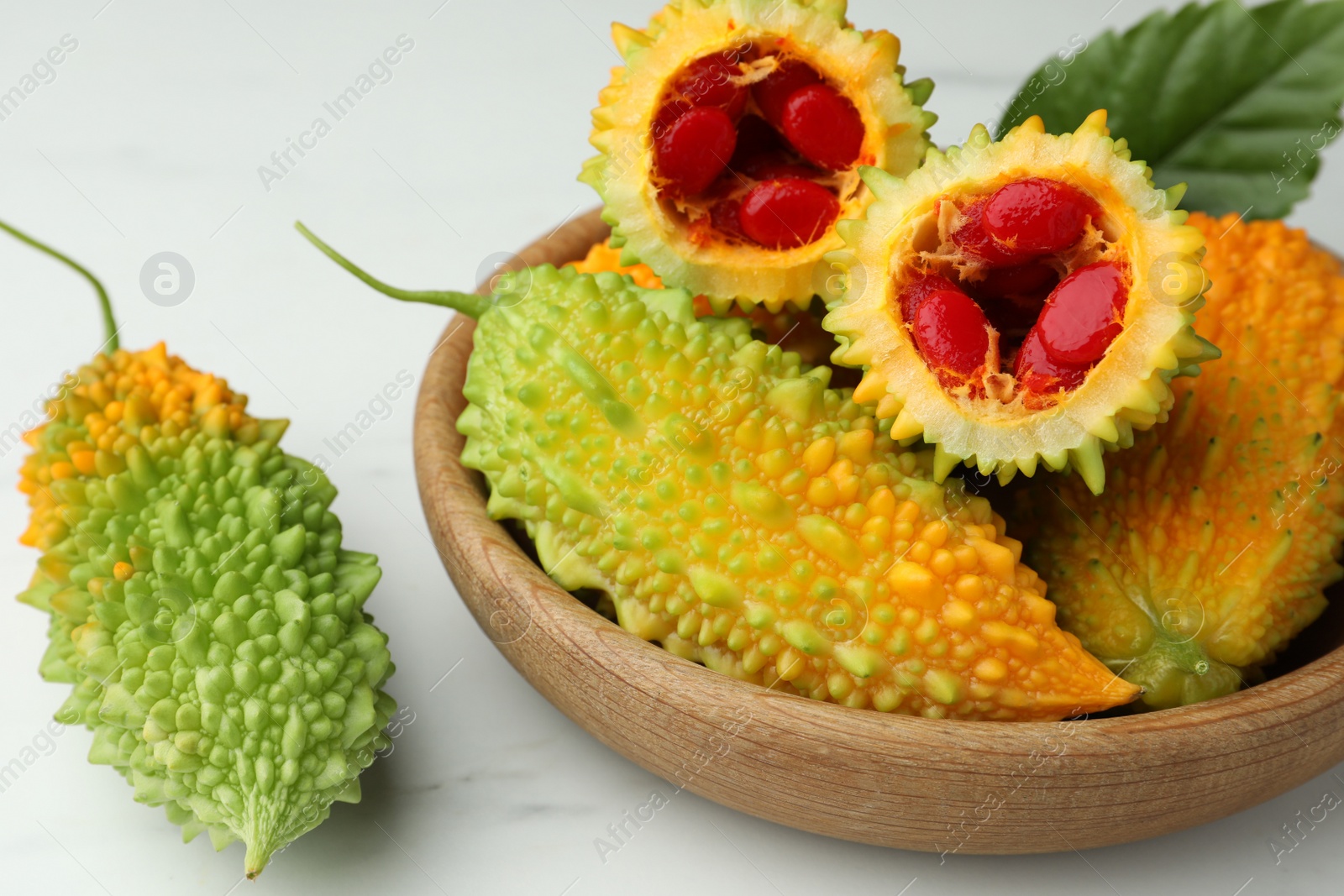 Photo of Fresh bitter melons on white marble table, closeup