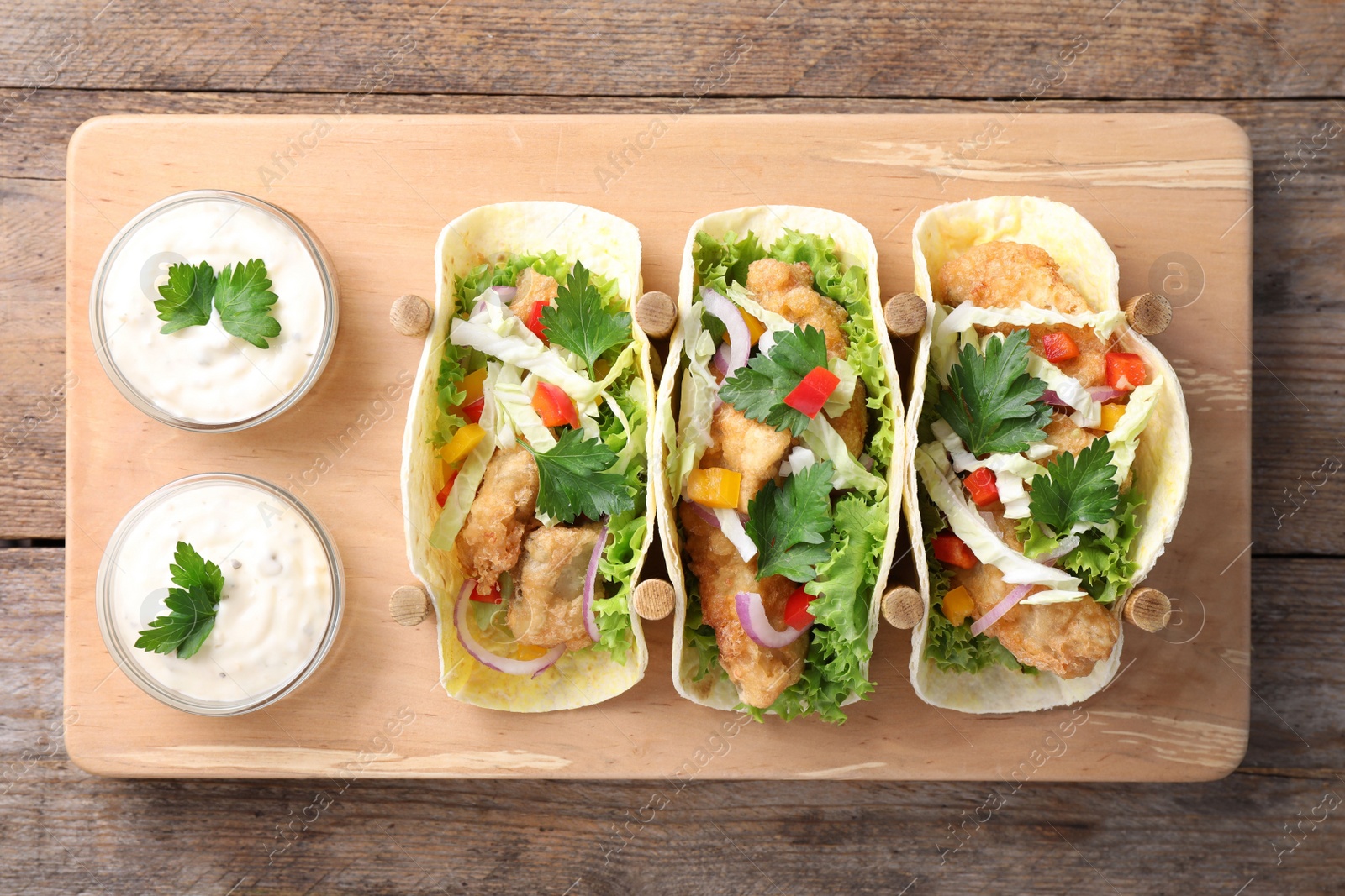 Photo of Yummy fish tacos served on wooden table, top view