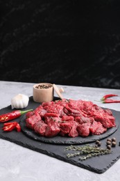 Photo of Pieces of raw beef meat, products and spices on grey textured table. Space for text