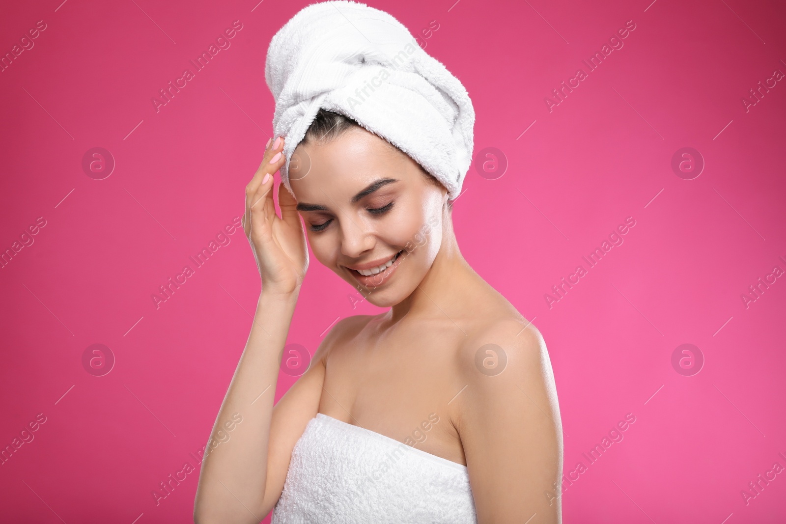 Photo of Happy young woman with towel on head against pink background. Washing hair