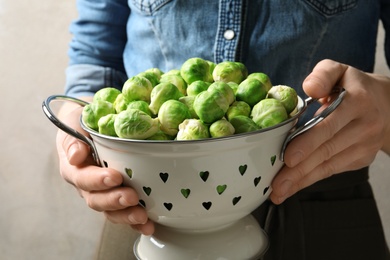 Photo of Woman holding colander with fresh Brussels sprouts, closeup