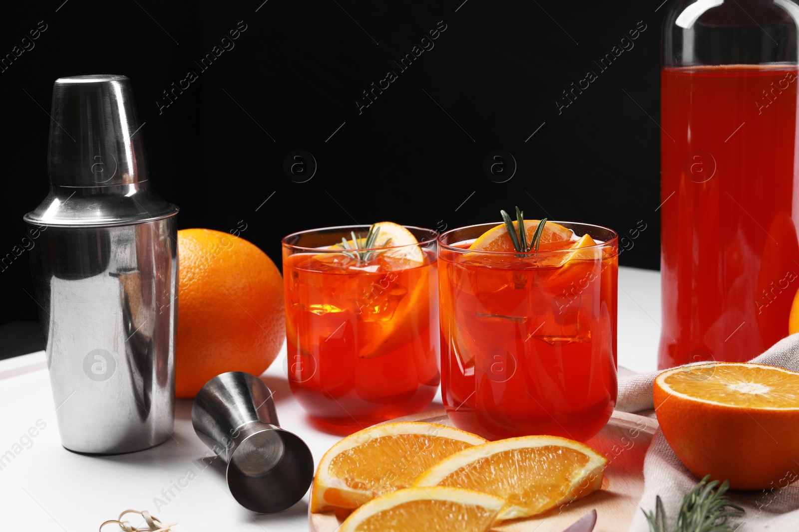 Photo of Aperol spritz cocktail, rosemary and orange slices on white table