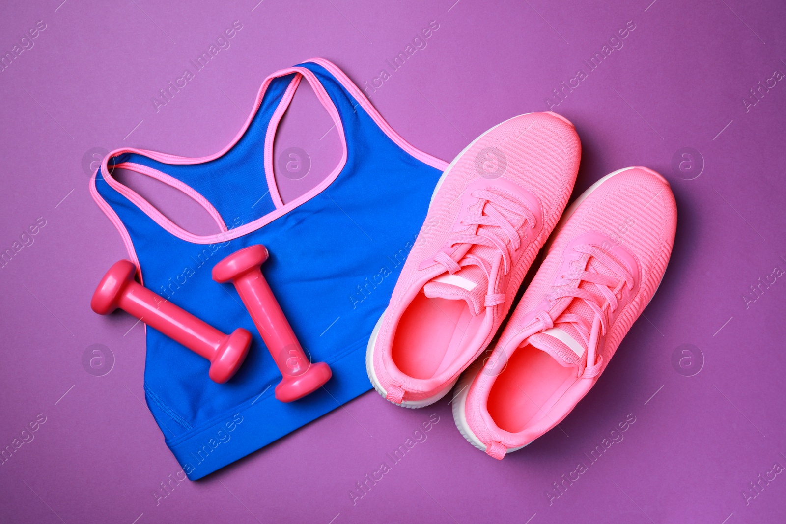 Photo of Stylish sportswear and dumbbells on purple background, flat lay