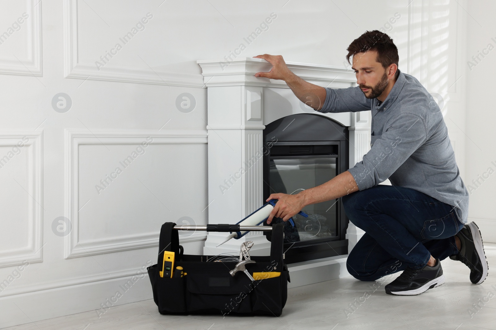 Photo of Man installing electric fireplace near white wall in room