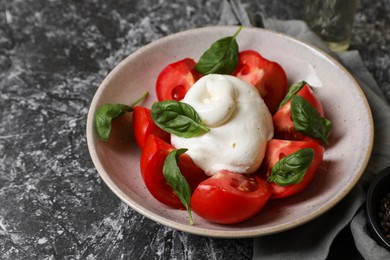 Delicious burrata cheese with tomatoes and basil on grey table, closeup. Space for text