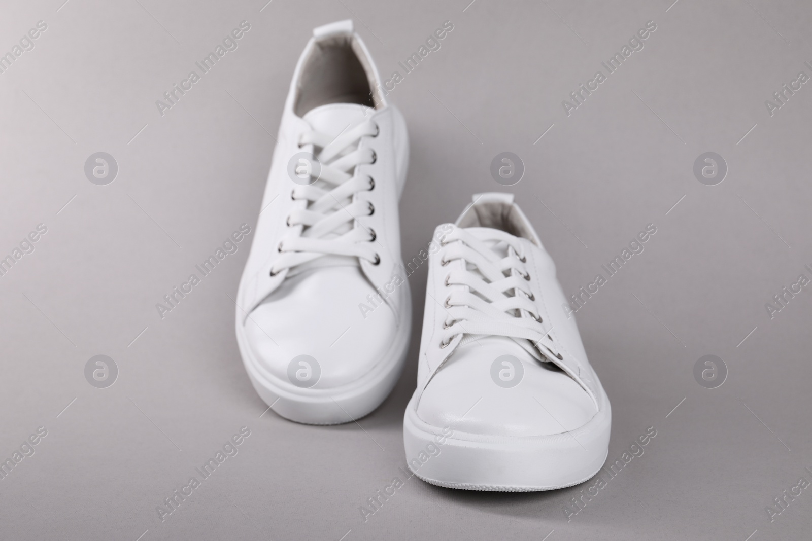 Photo of Pair of stylish white sneakers on grey background