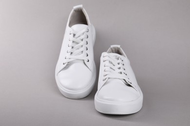 Photo of Pair of stylish white sneakers on grey background