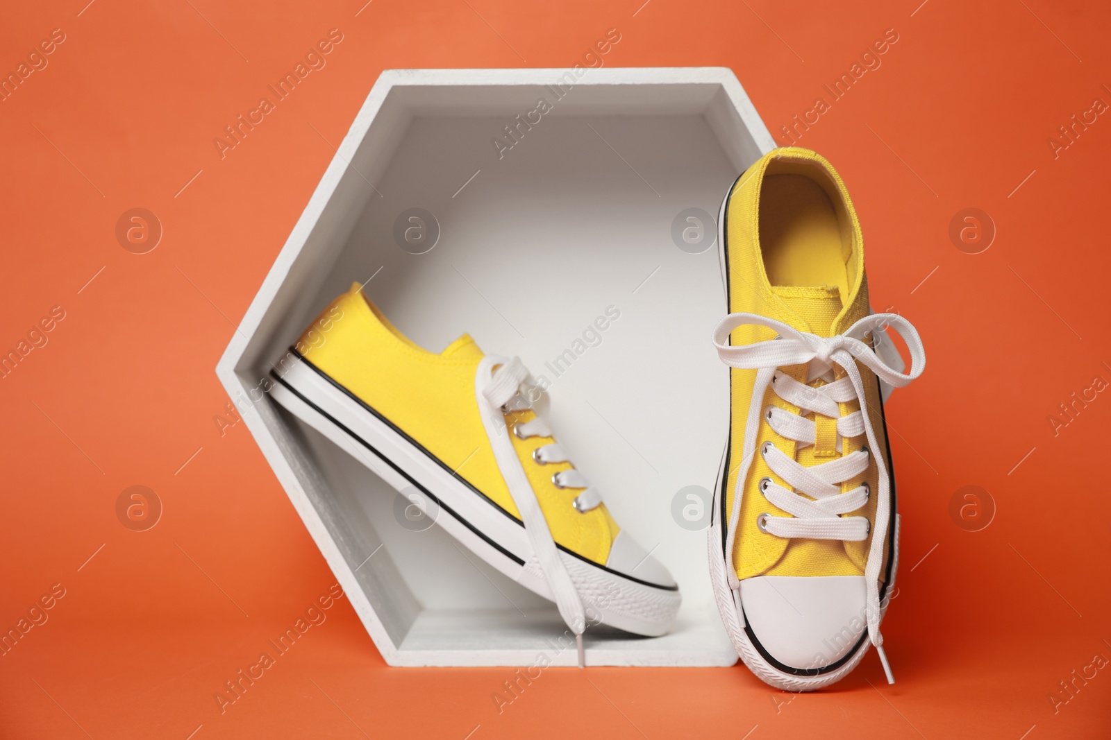 Photo of Stylish presentation of yellow classic old school sneakers against orange background