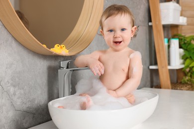 Photo of Cute little baby bathing in sink at home