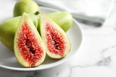 Plate with fresh ripe figs on marble background