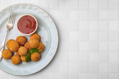 Photo of Delicious fried tofu balls with basil and sauce on white tiled table, top view. Space for text