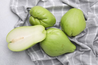 Cut and whole chayote on gray table, top view