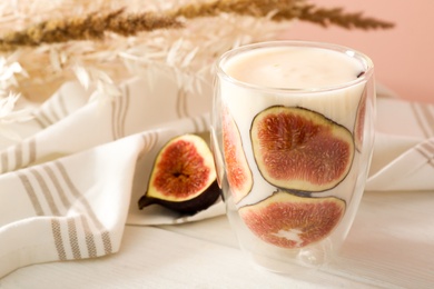 Delicious fig smoothie in glass on white wooden table