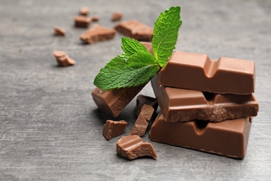 Pieces of milk chocolate with mint on gray table