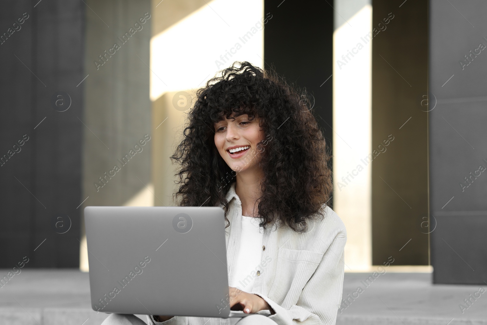 Photo of Happy young woman using modern laptop outdoors