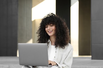 Happy young woman using modern laptop outdoors