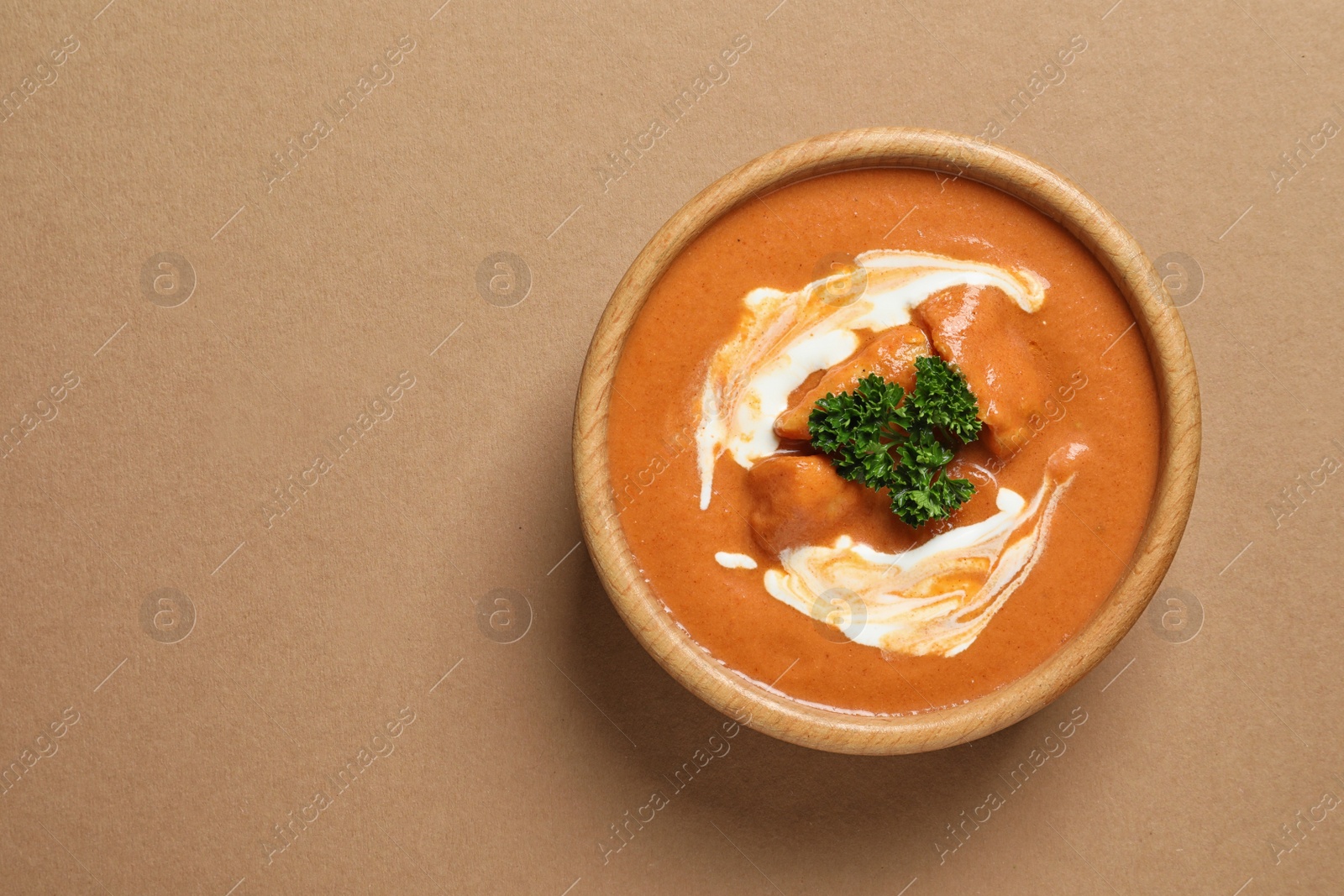 Photo of Bowl of delicious butter chicken on color background, top view with space for text. Traditional indian Murgh Makhani
