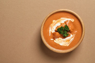 Bowl of delicious butter chicken on color background, top view with space for text. Traditional indian Murgh Makhani