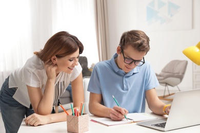 Mother helping her teenager son with homework indoors