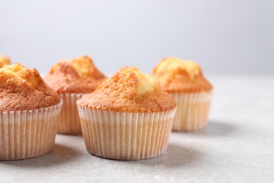 Photo of Delicious sweet muffins on light grey textured table, closeup. Space for text