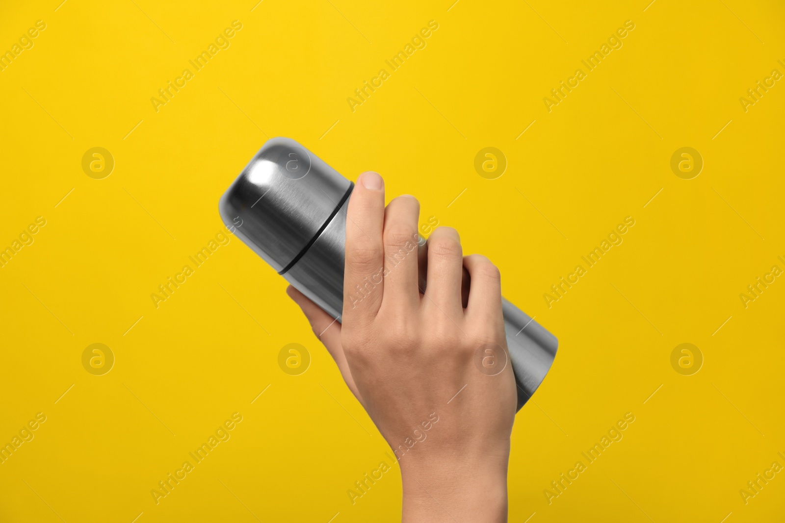 Photo of Woman holding modern thermos on yellow background, closeup