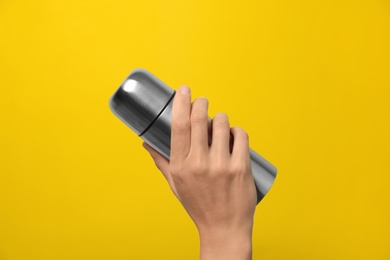 Photo of Woman holding modern thermos on yellow background, closeup