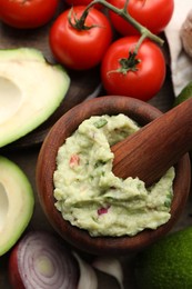 Photo of Mortar with delicious guacamole and ingredients on table, flat lay