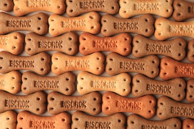 Photo of Bone shaped dog cookies on beige background, flat lay