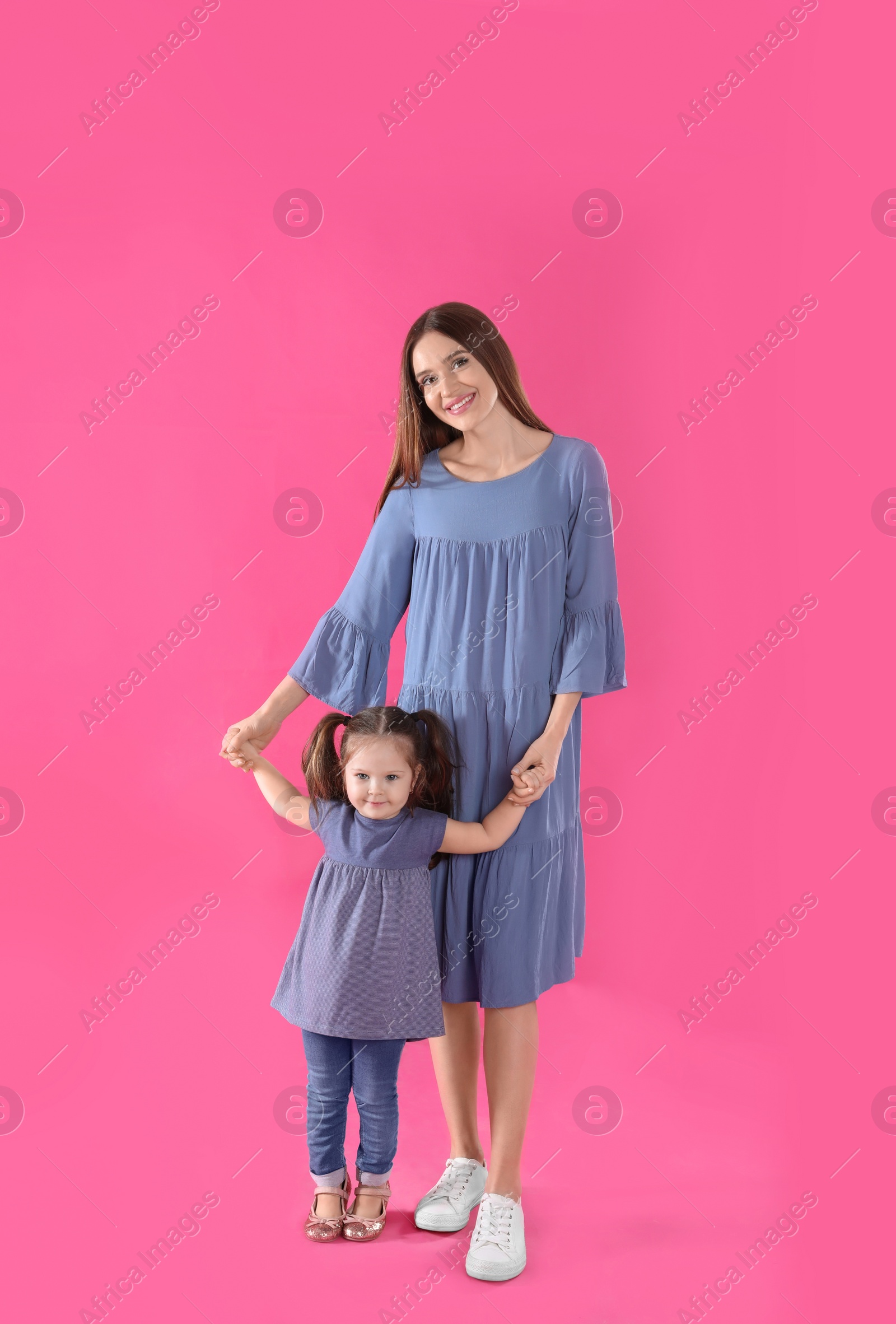 Photo of Young mother and little daughter on pink background