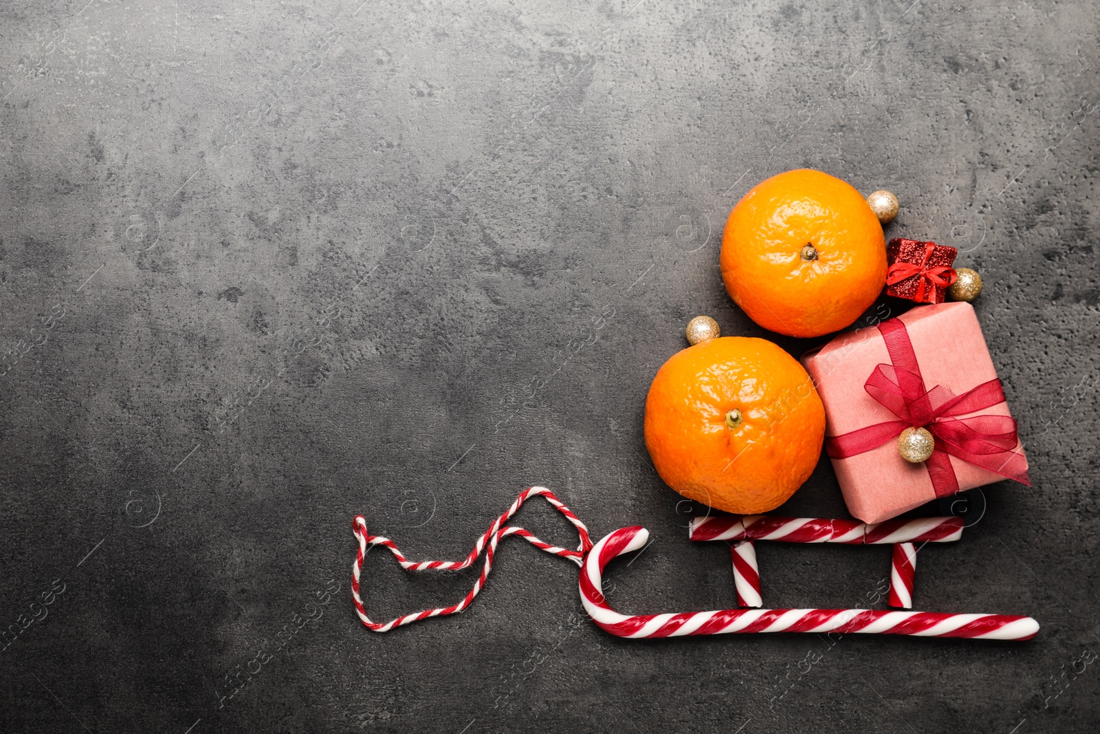 Photo of Flat lay composition with tangerine fruits, gift boxes and candy canes on grey table, space for text