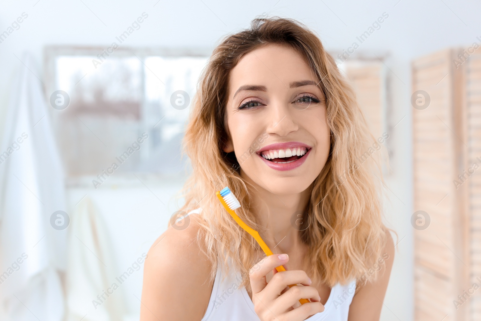 Photo of Young woman brushing her teeth in bathroom