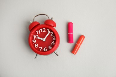 Photo of Tampons and red alarm clock on light background, flat lay