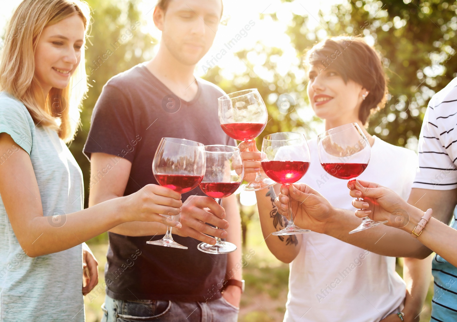 Photo of Young people with glasses of wine outdoors. Summer picnic