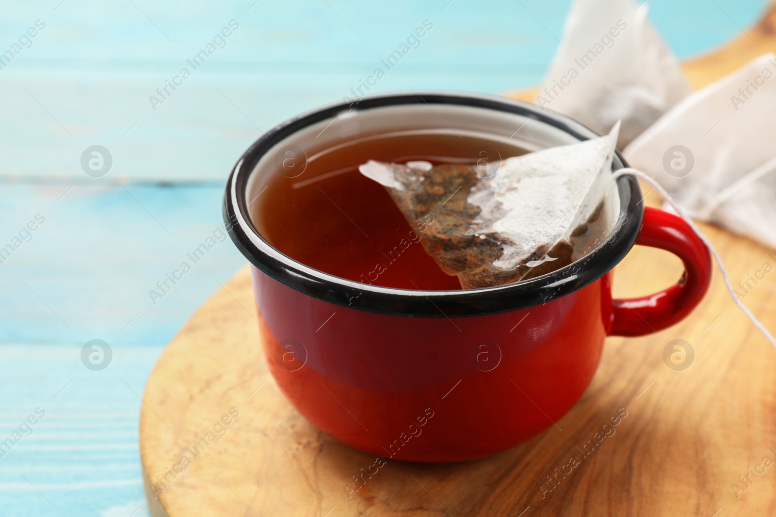 Photo of Tea bag in cup with hot drink on light blue wooden table, closeup