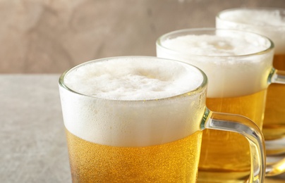 Glass mugs of cold tasty beer on table, closeup