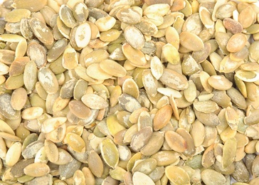 Photo of Raw peeled pumpkin seeds as background, top view