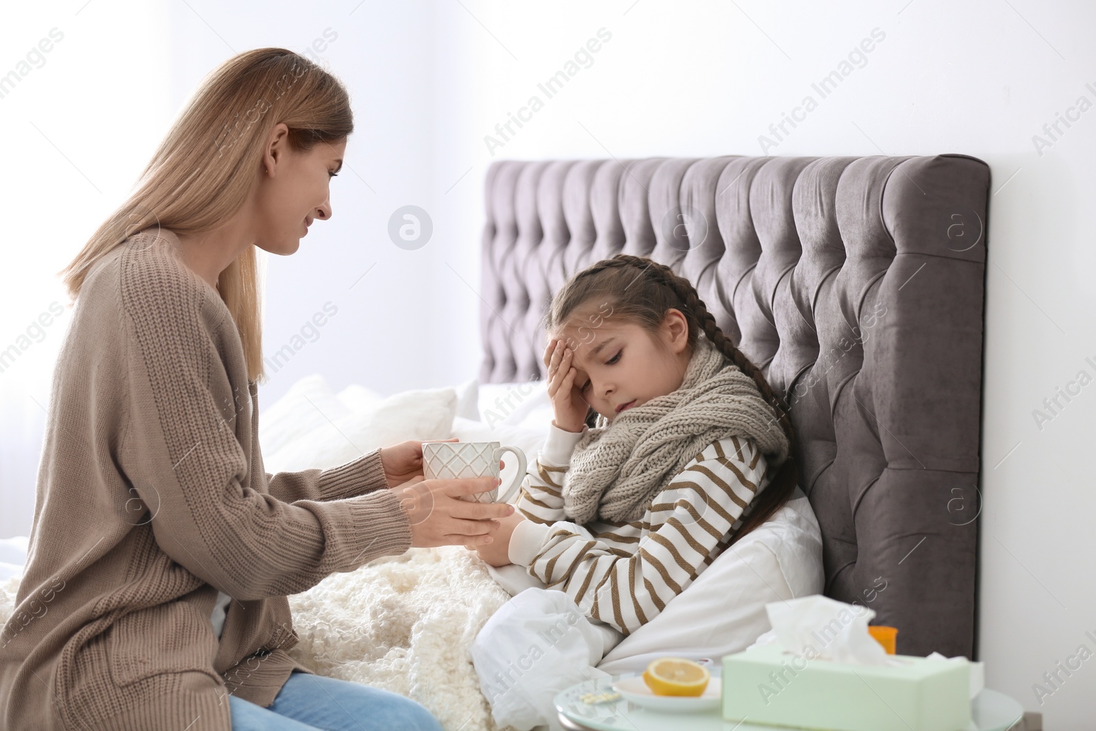 Photo of Mother taking care of little daughter suffering from cold in bed