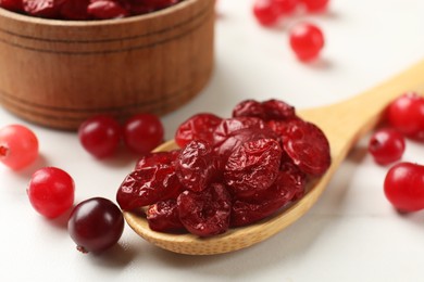 Photo of Tasty dried cranberries and fresh ones on white table, closeup