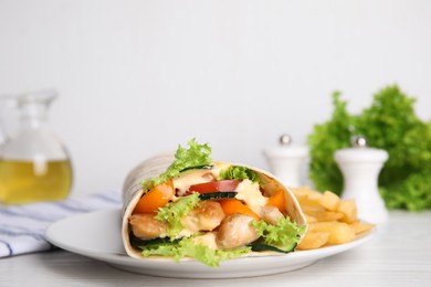 Photo of Delicious chicken shawarma and French fries served on white wooden table, closeup