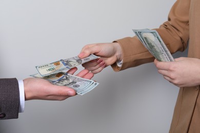 Photo of Woman giving money to man on light grey background, closeup. Currency exchange