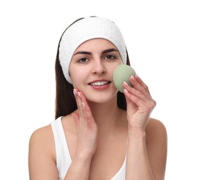 Photo of Young woman with headband washing her face using sponge on white background